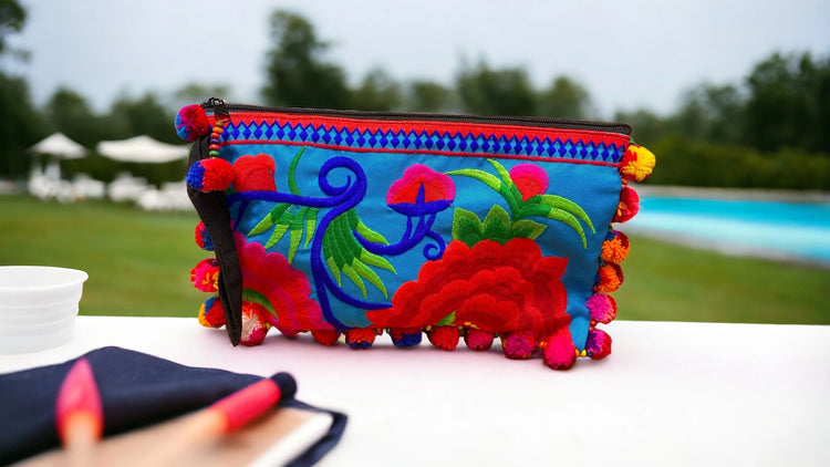 Pink and red blossom on marine blue with multi-coloured pom pom clutch